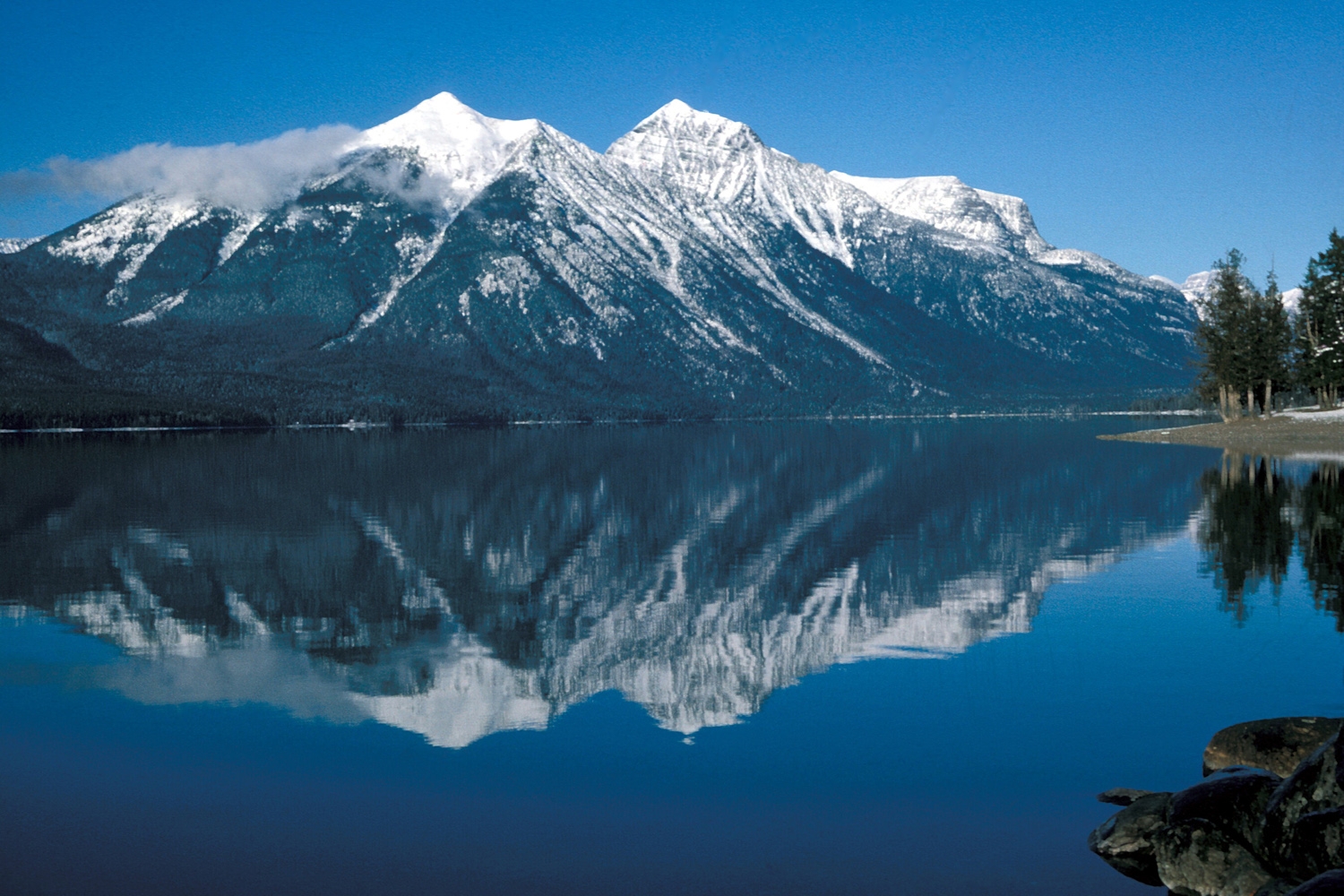 Lake McDonald in Glacier National Park, with still water below forested ridges and distant peaks